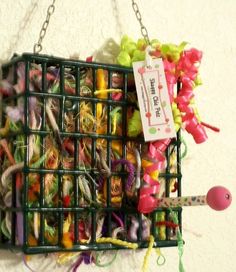 a bird cage filled with lots of different types of yarn and thread spools