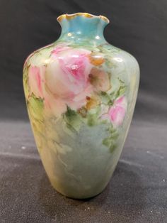 a vase with flowers painted on it is sitting on a gray surface and there is also a black background