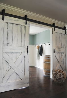 an open barn door in a living room with wood floors and white paint on the walls