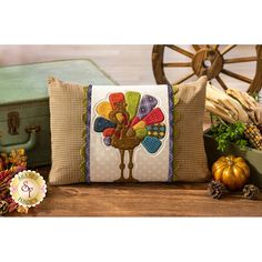 a pillow with a turkey on it sitting next to some pumpkins and other autumn decorations