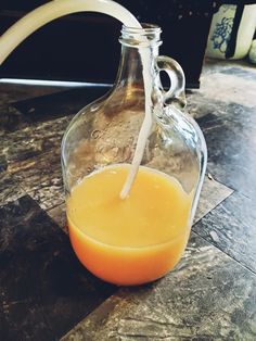 an orange juice is being poured into a glass jug