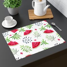 a place mat with watermelon slices on it next to a cup and saucer