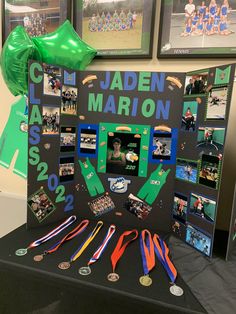 a table topped with pictures and medals next to green balloons in the shape of stars