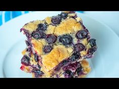 two pieces of blueberry crumb bars stacked on top of each other in a white plate