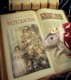 an open book with a mouse on top of it and a christmas tree in the background