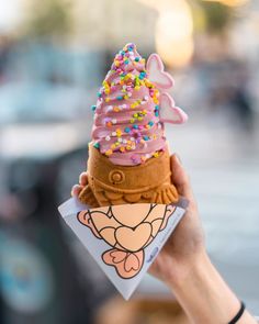 a person holding up an ice cream cone with sprinkles on it's top