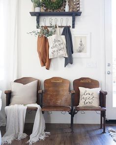 two wooden chairs sitting next to each other in front of a wall with pictures on it