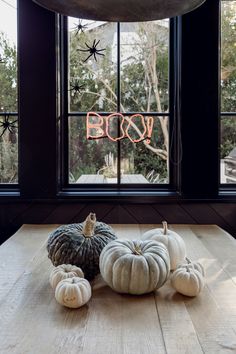 three pumpkins sitting on top of a wooden table in front of a large window