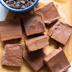 chocolate fudges are arranged on a plate with a bowl of cocoa chips next to it