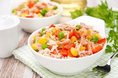 a white bowl filled with rice and vegetables next to a fork on top of a green napkin