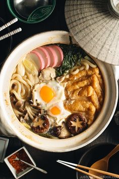 an overhead view of food in a bowl with chopsticks and other items on the table