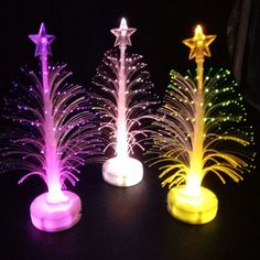 three different colored lights in the shape of trees with stars on each side and one has a white base