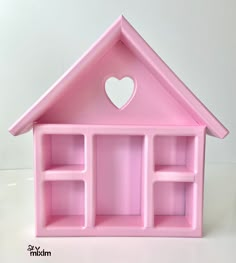 a pink doll house with shelves and a heart