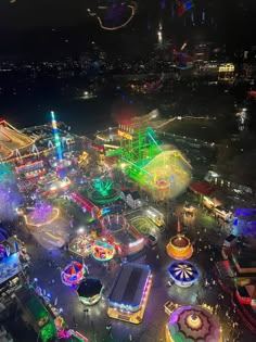 an aerial view of a carnival at night with lights on and rides lit up in the background