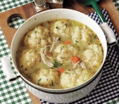 a white bowl filled with dumplings on top of a checkered table cloth next to a spoon