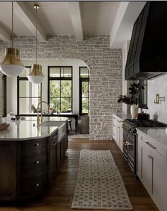 a large kitchen with an island in the middle and two pendant lights hanging from the ceiling