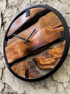 a clock made out of wood sitting on the side of a stone wall next to a tree