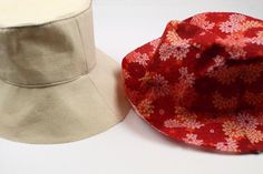 two hats sitting next to each other on top of a white table with red flowers