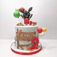 a birthday cake with balloons and an animal on top