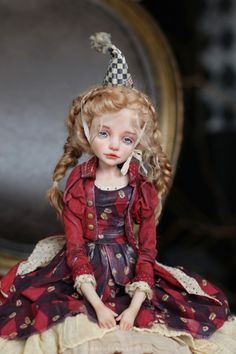 a doll sitting on top of a table wearing a red dress and a party hat