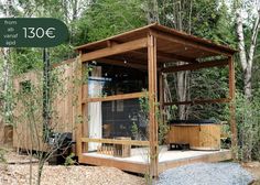 a wooden structure in the middle of some trees and rocks with a grill on it