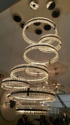 a large chandelier hanging from the ceiling in a room with people standing around