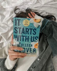 a woman laying in bed with her head on the book it starts with us by collien to over