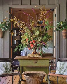 a table with flowers on it in front of some chairs and a basket full of plants