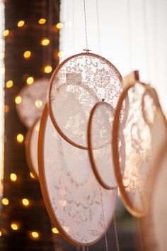 three white plates hanging from strings with lights in the background