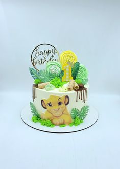 a lion themed birthday cake on a white plate with green leaves and swirly icing