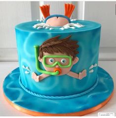 a blue cake with a boy wearing goggles and diving gear on it's side