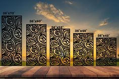 four panels with different designs on them in front of the sun and sky, set against a wooden floor