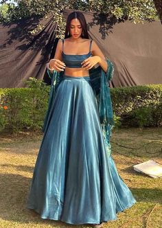 Step into refined elegance with this stunning blue teal lehenga crafted in luxurious gaji silk. The flared skirt is paired with a sleek sleeveless blouse, creating the perfect ensemble for bridesmaids looking to turn heads at sangeet or reception celebrations. A timeless statement piece for any festive occasion. Please note: The dupatta worn by the model is not by the designer. A customized dupatta can be provided upon request for an additional charge. Color: Blue Fabric: Gaji silk Components: S Teal Lehenga, Skirt With Blouse, Lehenga With Blouse, Teal Skirt, Sangeet Outfit, Simple Lehenga, Trendy Outfits Indian, Indian Outfits Lehenga, Lehenga Designs Simple