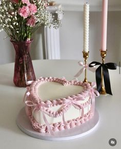 a heart shaped cake sitting on top of a table next to a vase with flowers