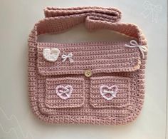 a crocheted pink purse with buttons on the front and side, sitting on a white surface