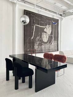 a black table and chairs in front of a wall with a cow painting on it