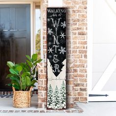 a sign that says winter on it next to a potted plant in front of a door