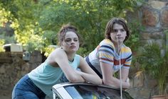 two girls leaning on the hood of a car