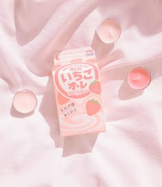 a carton of yogurt sitting on top of a bed next to three cups