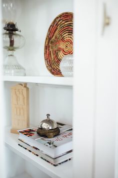 a white shelf with books and vases on it