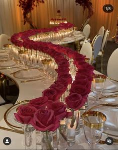 a long table is set with wine glasses and red roses in vases on it