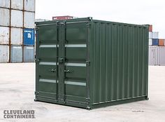 a green shipping container sitting on top of a parking lot next to some cargo containers