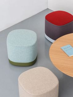 three different colored stools sitting on top of a gray floor next to each other