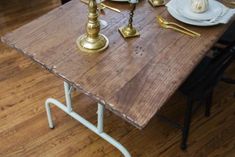 a wooden table topped with gold candlesticks and plates