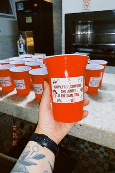 a person holding up a red cup with labels on it