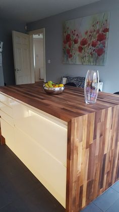 a kitchen island with a bowl of fruit on it and a wine glass next to it