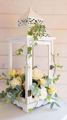 a white lantern with flowers and greenery on it