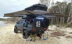 an off road vehicle parked on the beach with its roof tent attached to it's back