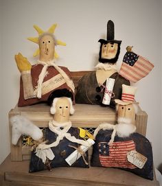 three wooden dolls sitting on top of a bench with american flags and other items around them