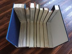 an open book sitting on top of a wooden floor next to a pile of books